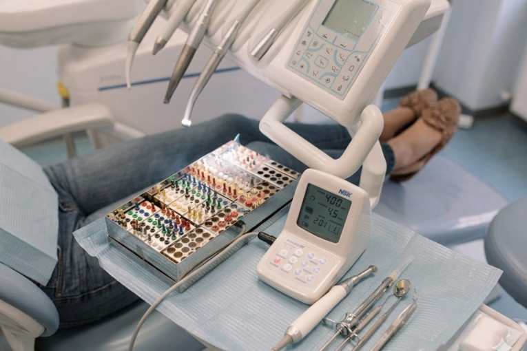 Instrumental de endodoncia sobre bandeja dental con limas de colores, piezas de mano y equipo de control.