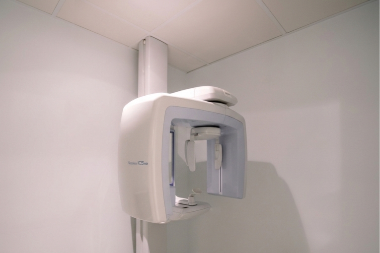 Equipo de ortopantomografía instalado en la consulta sobre fondo blanco.