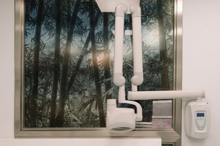 Equipo de radiología dental de pared junto a una ventana en la consulta.