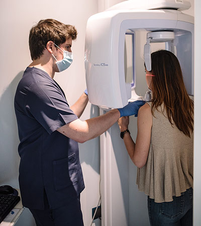 Profesional dental colocando a una paciente en un equipo de radiografía panorámica.